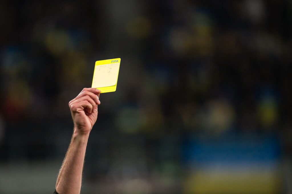 A referee shows a yellow card in the Premier League