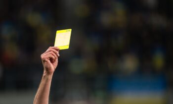 A referee shows a yellow card in the Premier League